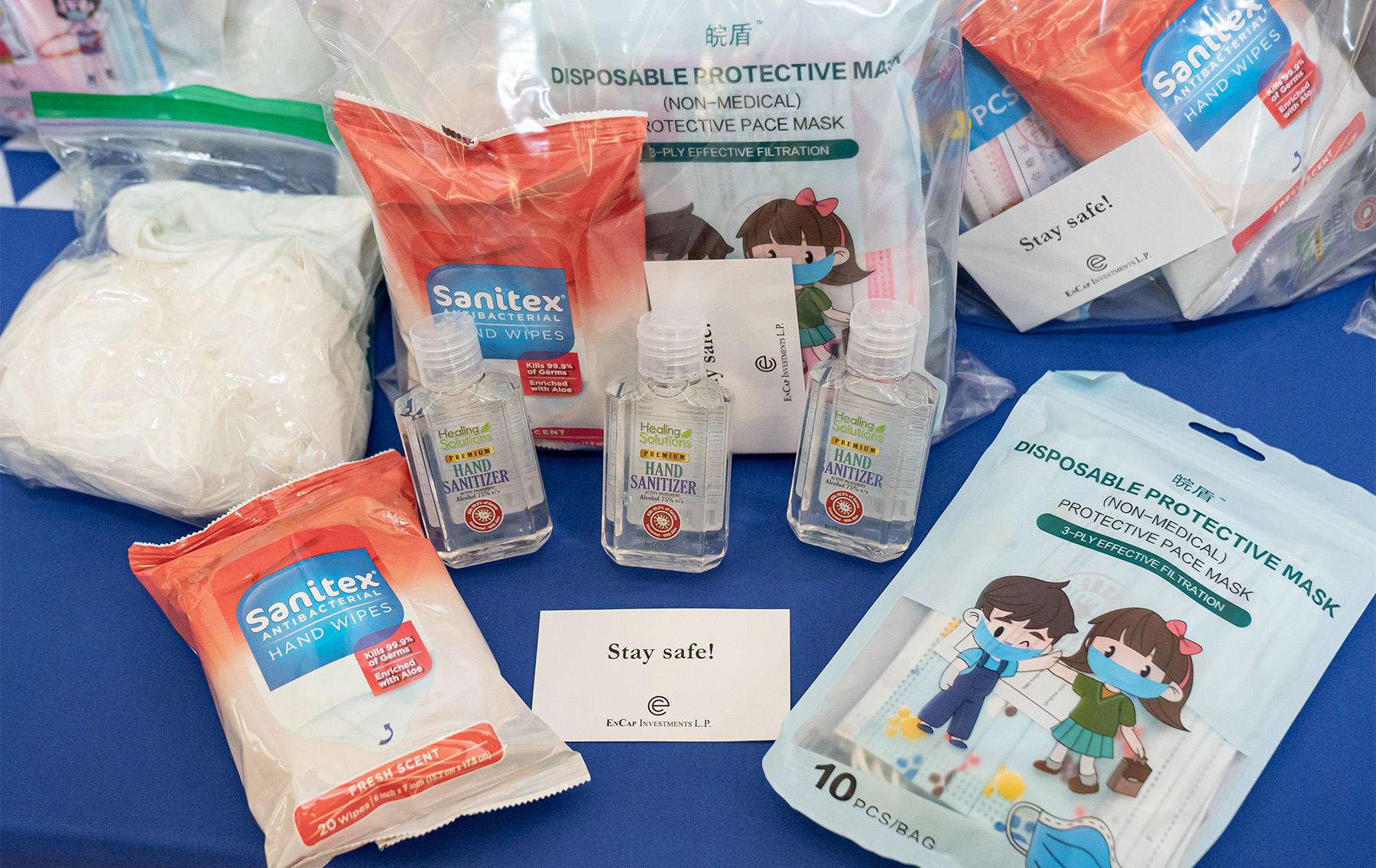 Contents of a COVID-19 safety kit are displayed along with an EnCap Investments “Stay safe!” card.