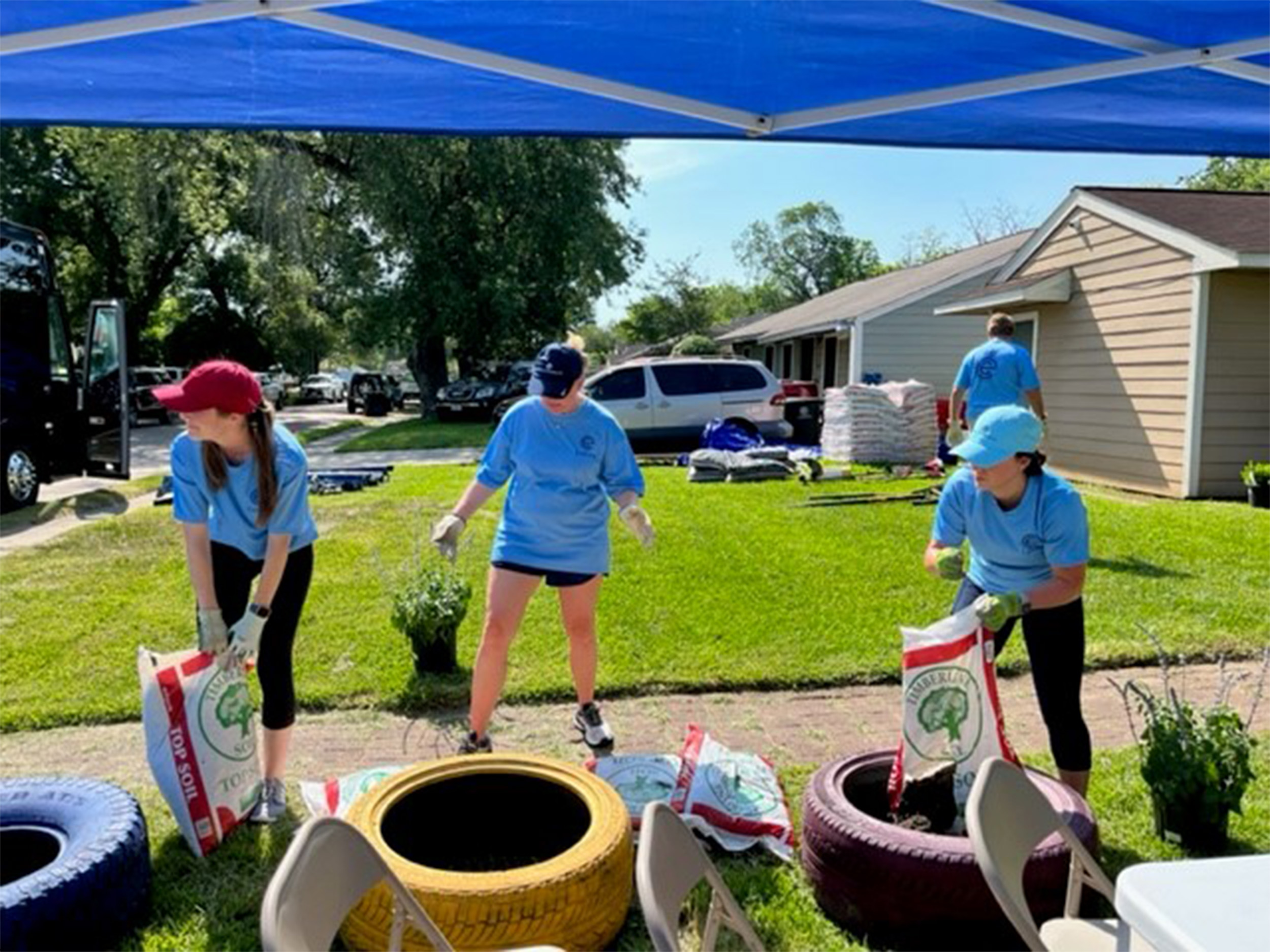 Jaclyn Marin (L), Katherine Cangelosi (C) and Cheryl Cheatham (R) repurpose tires into flower beds.