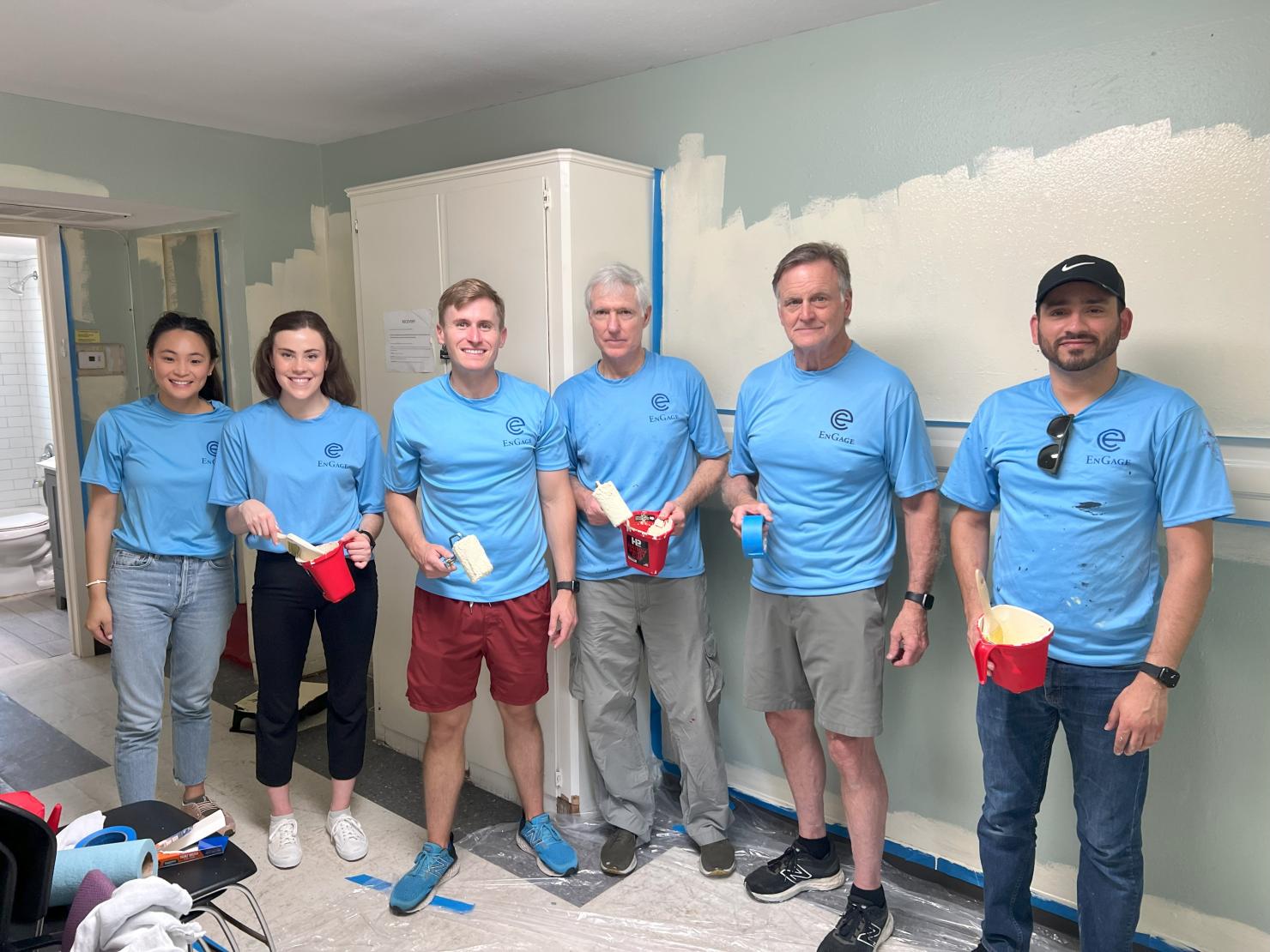 Employees pose for a picture as they make progress painting a small group activity room.Employees pose for a picture as they make progress painting a small group activity room.